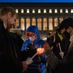 Mourners use a candle to light up their own candles at a vigil for Davide Giri, a Columbia University fatally stabbed.